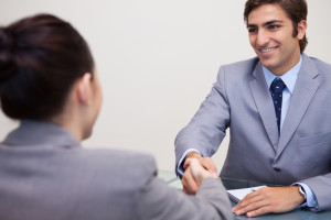 Hand shake at the end of a good job interview, both applicant and interviewer wear gray jackets